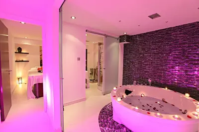a pink bathroom with a tub with a brick wall at Dome Beach Marina Hotel & Resort in Ayia Napa