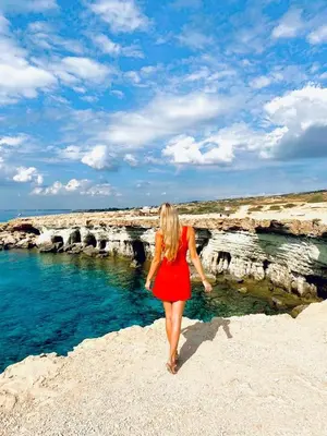 a woman in a red dress walking on the beach at Constantinos the Great Beach Hotel in Protaras