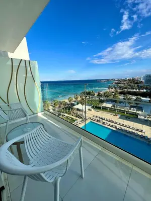 a balcony with two chairs and a view of the beach at Constantinos the Great Beach Hotel in Protaras