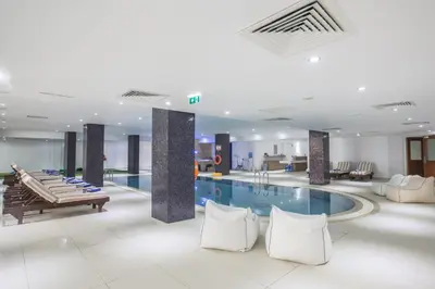 a hotel lobby with a pool and tables and chairs at Nelia Sea Breeze in Ayia Napa