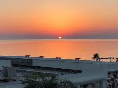 a sunset over the water with a building and the ocean at Anastasia Waterpark Beach Resort in Protaras