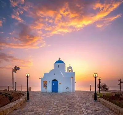a small white building with a blue door on the beach at Anastasia Waterpark Beach Resort in Protaras