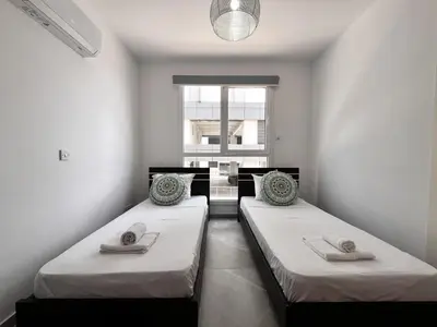 two beds in a room with a window at STAY NEO Coast Apartment in Limassol