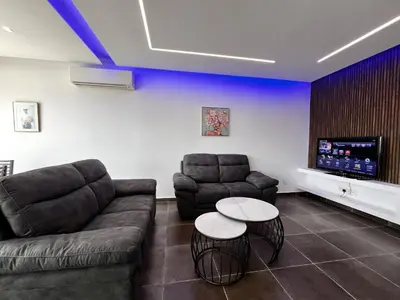 a living room with a couch and two tables and a flat screen tv at STAY NEO Coast Apartment in Limassol