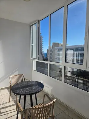 a table and chairs in a room with windows at 1 bd at Mediterranean Beach - Limassol Bay B206 in Limassol
