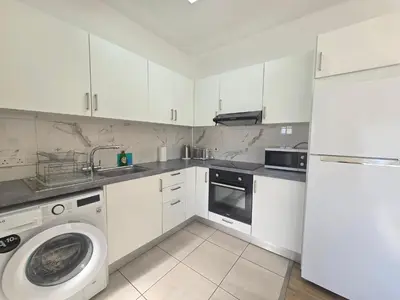a kitchen with white cabinets and a washing machine at 1 bd at Mediterranean Beach - Limassol Bay B206 in Limassol