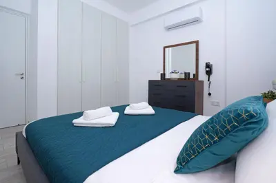 a bedroom with a bed with a blue blanket and a mirror at Villa Brigita in Ayia Napa