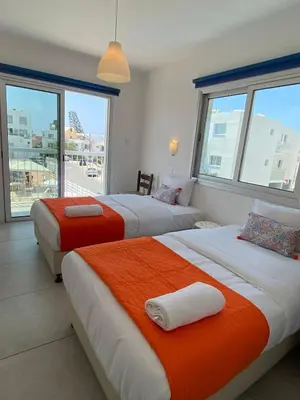 two beds in a hotel room with windows at Mangoes & Cherries in Ayia Napa