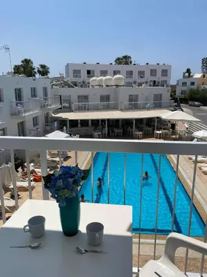 a balcony with a table with a vase of blue flowers at Mangoes & Cherries in Ayia Napa