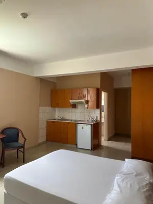 a bedroom with a white bed and a kitchen at Ellis Hotel Apartments in Larnaka