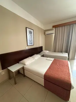 a hotel room with two beds and a window at Ellis Hotel Apartments in Larnaka