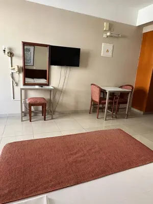 a living room with a table and chairs and a mirror at Ellis Hotel Apartments in Larnaka