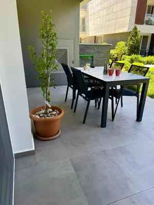 a patio with a table and chairs and a potted plant at Wakacyjny apartament w Courtyard Long Beach Holiday Resort in Iskele