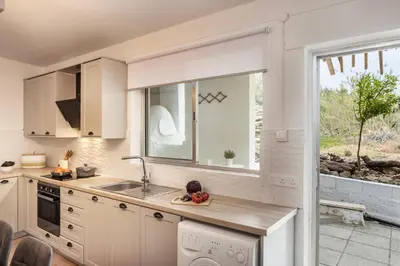 a white kitchen with a sink and a window at Galata Watermill Cottage in Nicosia