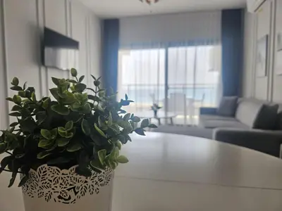 a white vase with a plant on a table in a living room at Seaview Apartment at Caesar Blue Complex Northern Cyprus H68 in Dherinia