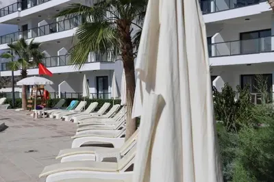 a row of white lounge chairs next to a building at Seaview Apartment at Caesar Blue Complex Northern Cyprus H68 in Dherinia