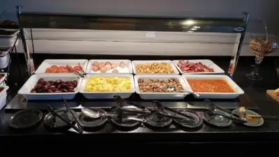 a counter with several trays of food and utensils at NÓA Rooms - Adults Only in Ayia Napa