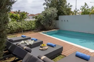 a backyard with a pool and two lounge chairs and a swimming pool at Sam's Villa in Paralimni