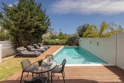 a swimming pool with chairs and a table next to a fence at Sam's Villa in Paralimni