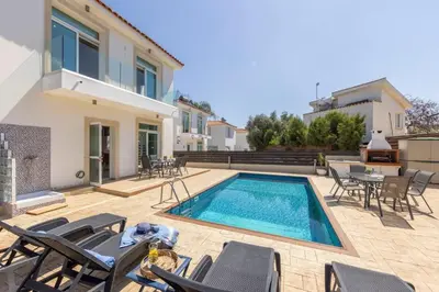 a villa with a swimming pool and chairs at Villa Parrog in Protaras