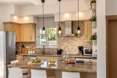 a kitchen with a large island with white chairs at Villa Parrog in Protaras