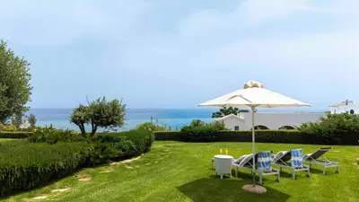 a lawn with two chairs and an umbrella at Sirena Solis Villa - Elegant 5-bedroom Sea View Retreat near Sirena Bay in Protaras