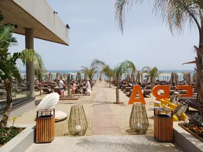 a walkway on the beach with chairs and palm trees at Grand Saphire Resort Apartment-I in İskele