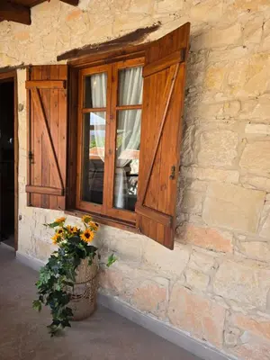 a window on the side of a stone building with flowers at Xenonas Hiliostrofi in Anoyira