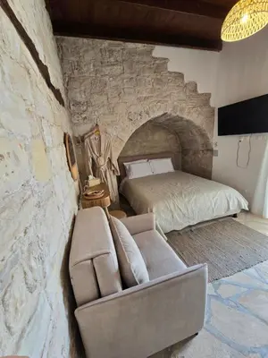 a bedroom with a bed and a couch in a stone wall at Xenonas Hiliostrofi in Anoyira