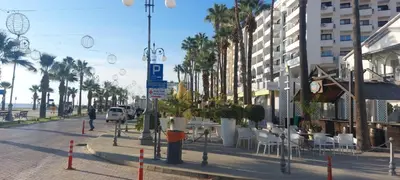 a street with palm trees and tables and chairs at 3 Bedroom Apartment Old Town Larnaca 5 minute walk to Finnikoudes Beach in Larnaka