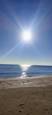 a beach with the sun shining over the water at 3 Bedroom Apartment Old Town Larnaca 5 minute walk to Finnikoudes Beach in Larnaka