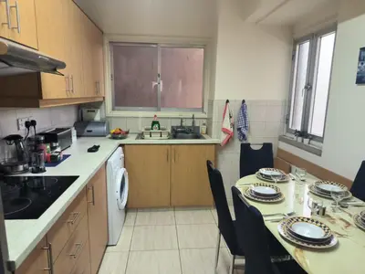 a small kitchen with a table and chairs and a sink at 3 Bedroom Apartment Old Town Larnaca 5 minute walk to Finnikoudes Beach in Larnaka