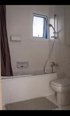 a bathroom with a tub and a toilet and a window at MERAKI Villa in Paralimni