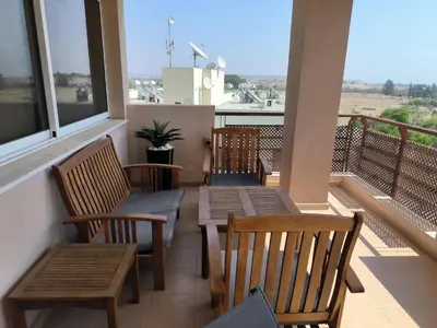 a balcony with wooden tables and chairs and windows at Superior 1 bed apartment in Oroklini with Communal Pool in Voroklini