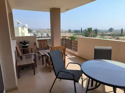 a balcony with tables and chairs and a view of the desert at Superior 1 bed apartment in Oroklini with Communal Pool in Voroklini