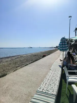 a beach with people sitting under an umbrella at Superior 1 bed apartment in Oroklini with Communal Pool in Voroklini