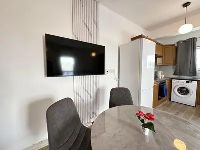 a dining room table with chairs and a television on a wall at Adonis Holiday Apt - Nicosia in Nicosia