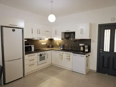 a kitchen with white cabinets and a white refrigerator at Family large apartment in Bahçeli in Aglantzia