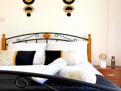 a bedroom with a bed with white sheets and pillows at Sunny Villa with Hot Tub, Garden and 2 Bedrooms, 5 Minutes to the Beach in Pyla