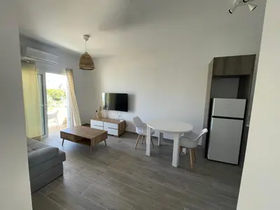a kitchen and living room with a table and a refrigerator at Green Bay Cosy Escape in Protaras