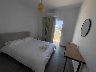 a bedroom with a bed and a table and a window at Green Bay Cosy Escape in Protaras