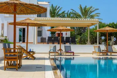 a pool with chairs and umbrellas next to a resort at Protaras Views Villa PRAM1 in Protaras