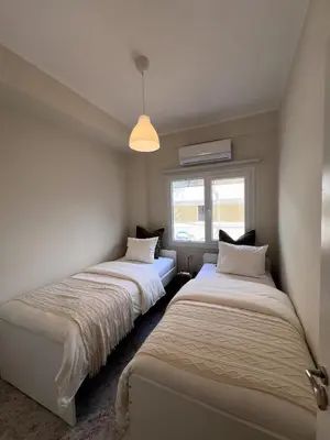 two beds in a room with a window at Casi-Homes in Larnaka