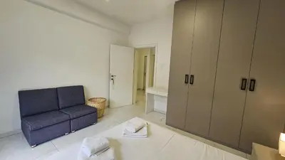 a living room with a blue chair and a cabinet at STAY Finibreeze Apartment in Larnaka