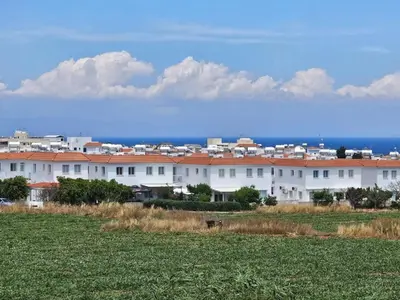 a large white building with red roofs in a field at Kapparis - Blue and aqua in Paralimni
