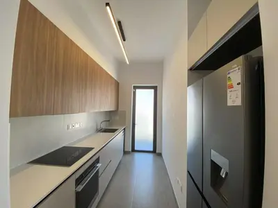 a kitchen with white counters and wooden cabinets at 1 bedroom 104 in Limassol