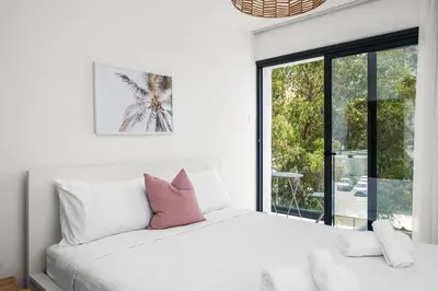 a white bedroom with a bed and a window at Majan Residences in Larnaka