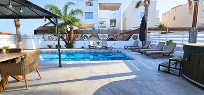 a patio with a pool and chairs and a table at Villa Elia Blue , hot tube , heated pool in Paralimni
