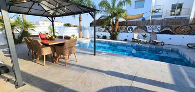 a patio with a table and an umbrella next to a pool at Villa Elia Blue , hot tube , heated pool in Paralimni