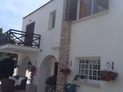 a white building with a porch and a balcony at Fig Tree Bay Villa Elena in Protaras